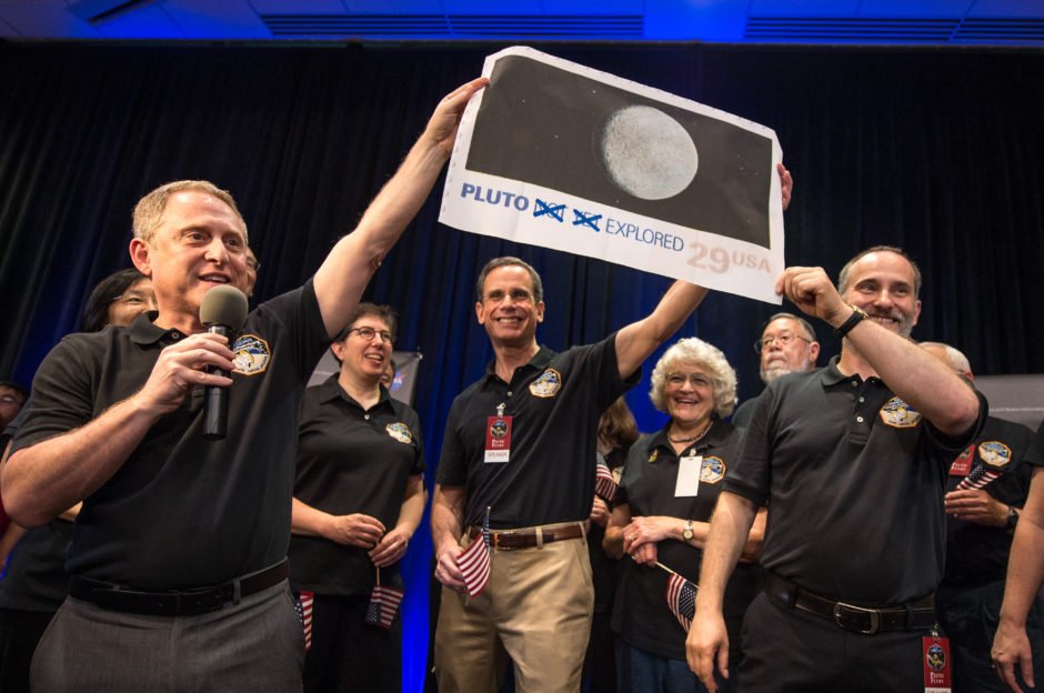 Alan Stern, líder del equipo de la sonda espacial New Horizons, sostiene una reproducción de la estampilla con un par de correcciones. 